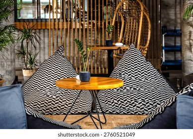 Cozy lounge space featuring patterned bean bag chairs, a wooden coffee table, and natural decor elements. The modern boho-style interior includes plants, textured walls, and warm lighting, creating a relaxing and inviting atmosphere perfect for socializing or unwinding.