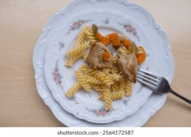 cozy meal of pasta, stewed meat, and vegetables on classic ceramic plate with floral design, served with fork - Powered by Shutterstock