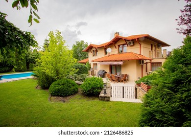 Cozy Mediterranean Orange House With Fresh Green Spring Garden, And With A Pool In The Background