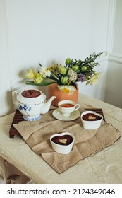 A Cozy Minimal Table Setting With Tablecloth, Pink Vase With Flowers, Tea, And Dessert Tiramisu With Heart