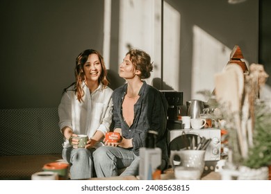 Cozy morning: girls friends talking over a cup of coffee in a bright kitchen Two women spend time peacefully on a sunny day with mugs of tea - Powered by Shutterstock