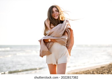 Cozy outdoor image of brunette woman , beige natural colors, wearing big cashmere scarf, windy weather, freedom concept.