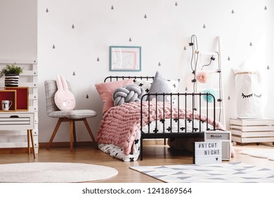 Cozy pastel pink woolen blanket on single industrial bed in scandinavian bedroom interior for teenager