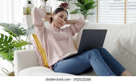 Cozy relax young attractive asian female employee wear earphone listen to digital online course development program in quarantine social distance at home reskill upskill school class for career path. - Shutterstock ID 1923121268