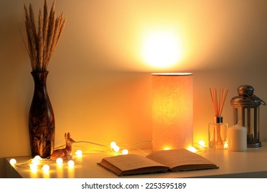 cozy room table with warm light lamp and old book - Powered by Shutterstock
