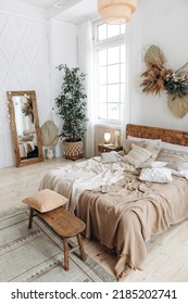 Cozy Rustic Bedroom With Boho Ethnic Decor. Bright Spacious Apartment With Large Windows. Wooden Furniture. Large Mirror. Handmade Textile. Plants In The Interior. Nobody.