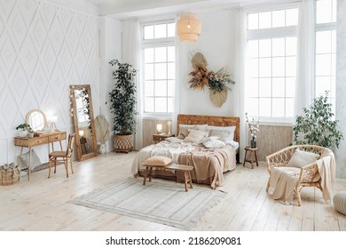 Cozy Rustic Bedroom With Boho Ethnic Decor. Bright Spacious Apartment With Large Windows. Nobody. Wooden Furniture. Boudoir Table. Large Mirror. Handmade Textile. Plants In The Interior.