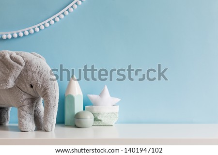 Cozy scandinavian newborn baby room with gray plush elephant ,white stars lamp and children accessories. Stylish interior with blue walls and haniging white garland. Template. Copy space. 