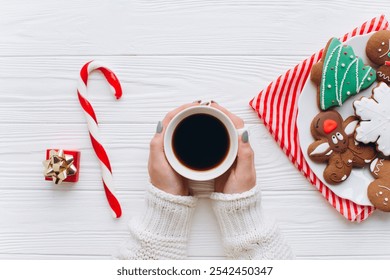 A cozy setup featuring a warm cup of coffee, Christmas-themed cookies, and a red-white candy cane. Perfect for festive inspiration and holiday cheer.