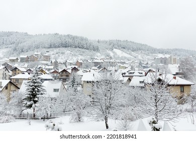 Cozy Small European Town On A Hillside On A Snowy Winter Day. The Village Houses And Forest Are Covered With Fresh Snow.