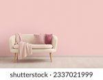 Cozy sofa with cushions and blanket near pink wall