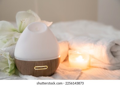 Cozy spa composition with aroma diffuser, burning candle, towels and flowers on a blurred background, copy space. - Shutterstock ID 2256143873