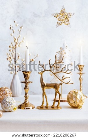 Cozy still life with burning candles, figure of deer and Christmas decorations on pastel light background. Christmas composition for home interior
.