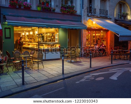 Cozy street with tables of cafe in Paris, France. Night cozy cityscape of Paris. Architecture and landmarks of Paris. 