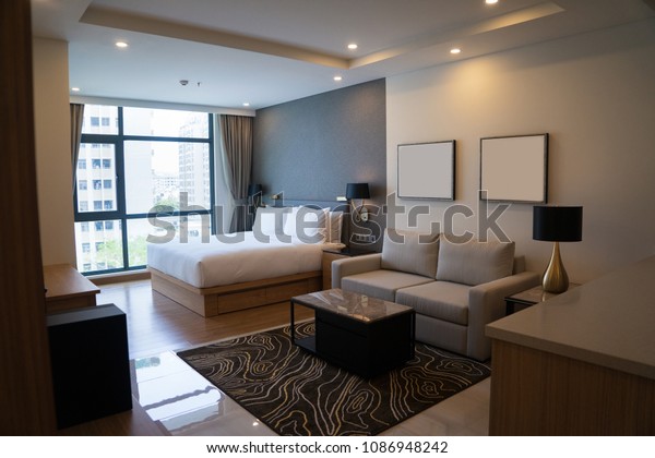 Cozy studio apartment design with\
bedroom and living space. Hotel room panoramic window, double bed,\
sofa and coffee table. Urban apartment\
concept