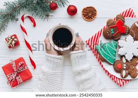 A cozy tabletop scene featuring a warm cup of coffee, festive cookies, and Christmas decorations. The image exudes holiday cheer with gifts, candy canes, and vibrant, seasonal colors.