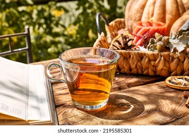 Cozy Warm Autumn Composition With Cup Of Hot Tea, Burning Candle, Open Book And Pumpkins On Wooden Background. Autumn Home Decor. Fall Mood. Thanksgiving. Halloween.