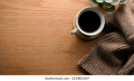 Cozy Warm Comfortable Workspace With Black Coffee Cup, Brown Sweater, Decor Plant And Copy Space On Wooden Background. Overhead, Top View