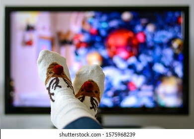 Cozy warm winter christmas socks with a reindeer. Person watching a christmas movie on the television. 