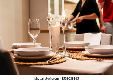 Cozy white interior. Served table. A young pregnant couple getting ready for dinner. Great feeling of home.