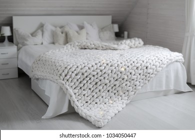 Cozy white scandinavian bedroom interior. Beautiful merino woolen plaid decorated bed and floor, super chunky yarn knitted blanket, nobody - Powered by Shutterstock