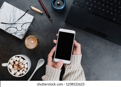 Cozy winter business flatlay arrangement with black laptop, women hands with vegan cocoa and candles on dark marble background