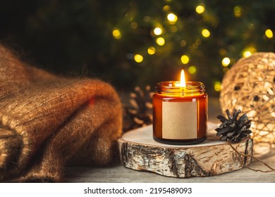 Cozy winter card with burning aroma candle in a dark glass jar with empty label mock up and wool sweater over blurred bokeh lights on the background. Christmas holiday at home. - Powered by Shutterstock