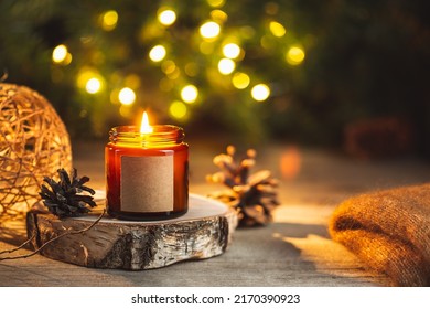 Cozy winter evening card with burning aroma, candle in a dark glass jar with empty label mock up. Soft focus, copy space for text. Blurred bokeh lights on the background. Christmas holiday at home. - Powered by Shutterstock