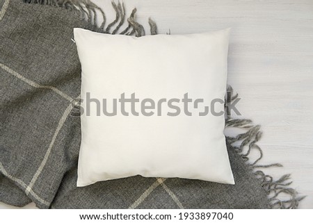 Cozy winter flat lay composition with white blank pillow and warm wool blanket, square pillow case, cushion mockup.      