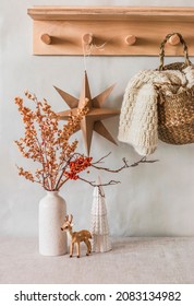 Cozy Winter Interior - Dried Flowers In A Vase, A Homemade Scandinavian Christmas Star, Books, Christmas Decorations, A Knitted Plaid In A Jute Basket On A Wooden Shelf   