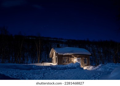 Cozy Wintry Ski Resort Cottage Snowcapped roof And Illuminated Windows with clear dark blue starry Sky in the Woodlands of North Sweden. - Powered by Shutterstock