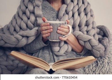 Gemütliche Frau mit warmer, weicher Merino-Wolldecke, die ein Buch liest. Entspannen Sie sich und genießen Sie einen komfortablen Lebensstil.