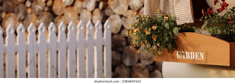 A cozy wooden shed with a lot of firewood in a tidy green yard with potted plants and flowers. Concept for home improvement, gardening, or rural lifestyle. Banner with copy space. - Powered by Shutterstock