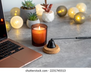Cozy working space table decor. Succulents, burning candle, lights and laptop at home office. Relaxing atmospehere for autumn or winter. Comfortable home concept, interior New Year. Selective focus.