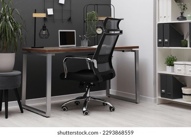 Cozy workplace with modern laptop on desk and comfortable chair at home - Shutterstock ID 2293868559
