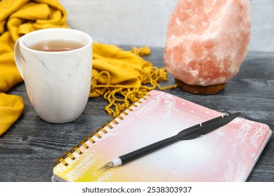 Cozy Workspace with Himalayan Salt Lamp, Cup of Tea, Yellow Scarf, and Notebook for Relaxed Journaling and Mindfulness - Powered by Shutterstock