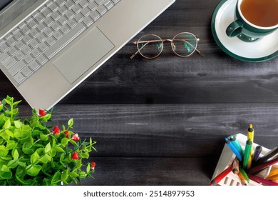 Cozy Workspace with Laptop and Coffee Cup. A well-organized workspace featuring a laptop, eyeglasses, and a cup of tea on a dark wooden desk. - Powered by Shutterstock