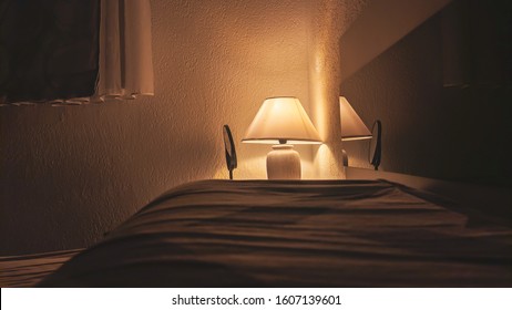 Cozy Yellow Light Coming From The Lamp During Evening In The Dark Bedroom Next To The Bed Making A Romantic Atmosphere For Reading Or Relaxing