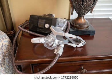 CPAP machine sitting on night stand with face mask and tubing.