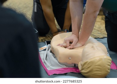 CPR First Aid Training with CPR dummy in the class. Demonstrating chest compressions concept