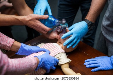 CPR practitioner examining airway passages on infant dummy. Model dummy lays on table and two doctors practice first aid - Powered by Shutterstock