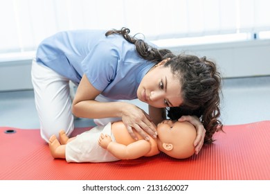 CPR practitioner examining airway passages on infant dummy. Model dummy lays on table and two doctors practice first aid. - Powered by Shutterstock