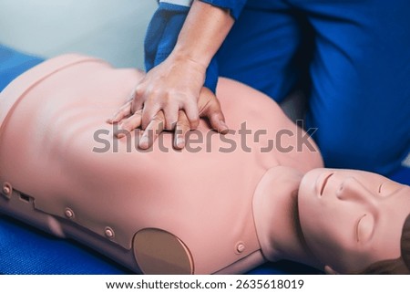 CPR Training, Emergency First Aid Class Demonstrating Chest Compressions on a CPR Doll for Cardiopulmonary Resuscitation in Realistic Simulation