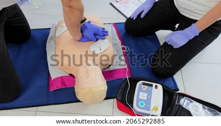 CPR training medical procedure workshop. Demonstrating chest compressions and use of AED automatic defibrillator on CPR doll