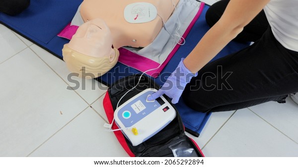 CPR training medical procedure workshop.\
Demonstrating chest compressions and use of AED automatic\
defibrillator on CPR doll