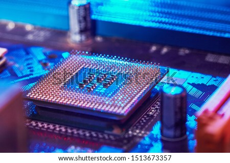 CPU desktop with the contacts facing up lying on the motherboard of the PC. the chip is highlighted with blue light. Technology background. selective focus
