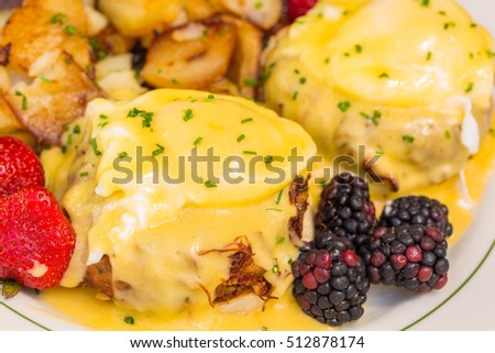 Crab cake eggs benedict served with berries and german potatoes