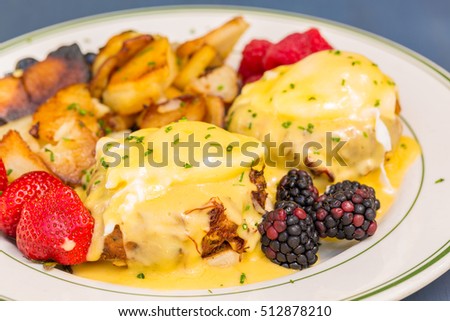 Crab cake eggs benedict served with berries and german potatoes