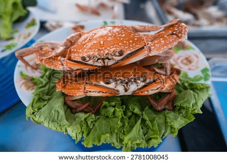 Crab Delight: Two delectable cooked crabs rest on a bed of fresh greens, presented on a decorative plate, a culinary delight.
