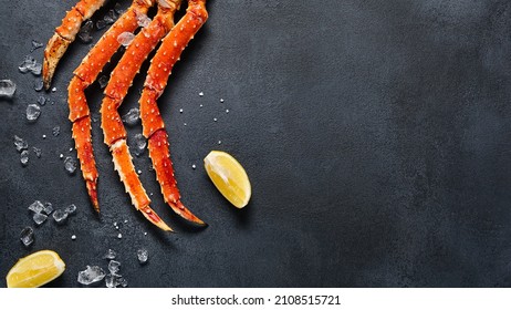 Crab legs top view on dark background. Delicatessen crab seafood on black slate table. Crustacean seafood aesthetics. Luxury crab meat food flat lay. Seafood menu background with alaskan crab legs